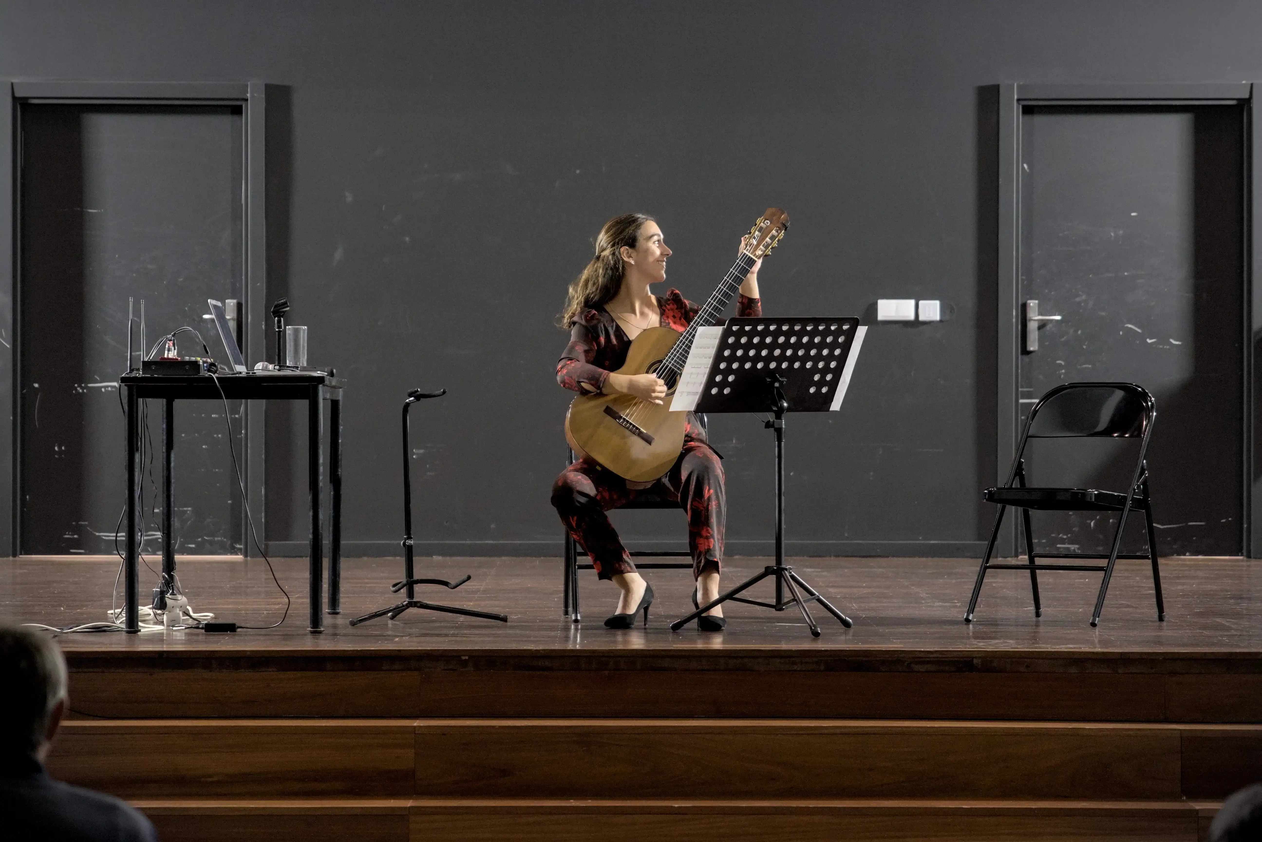 Uma mulher toca guitarra clássica num palco.